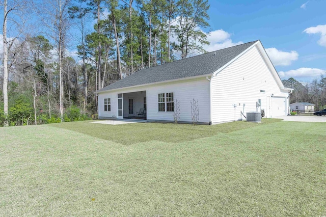 back of house featuring a garage, a yard, a patio area, and central AC