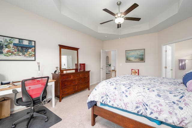 bedroom featuring a raised ceiling, light colored carpet, and ceiling fan