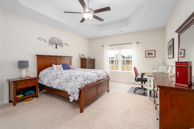 carpeted bedroom featuring ceiling fan and a tray ceiling