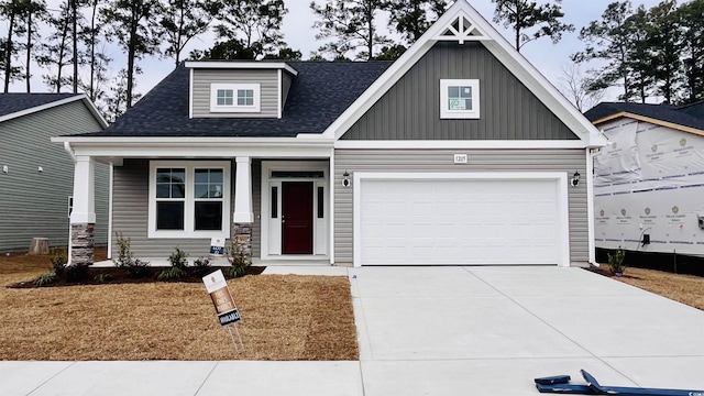 craftsman house featuring a garage, driveway, a shingled roof, and board and batten siding