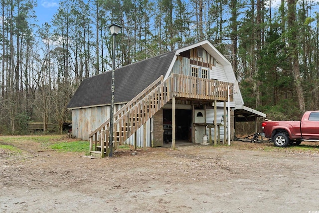 exterior space featuring a shingled roof, a wooden deck, stairway, and a gambrel roof