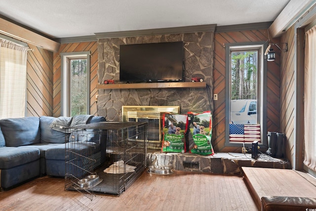 living area with wood walls, a fireplace, wood finished floors, and a textured ceiling