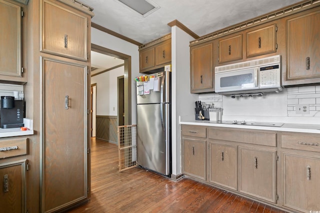 kitchen featuring white microwave, ornamental molding, dark wood-style flooring, freestanding refrigerator, and light countertops