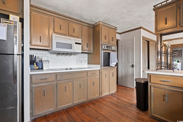 kitchen featuring oven, white microwave, light countertops, and freestanding refrigerator