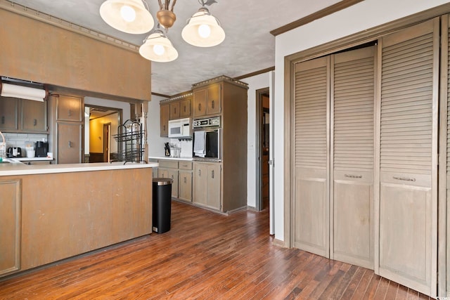 kitchen with white microwave, dark wood-style floors, light countertops, pendant lighting, and black oven