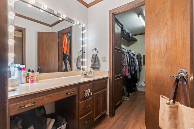 full bathroom with a spacious closet, wood finished floors, vanity, and crown molding