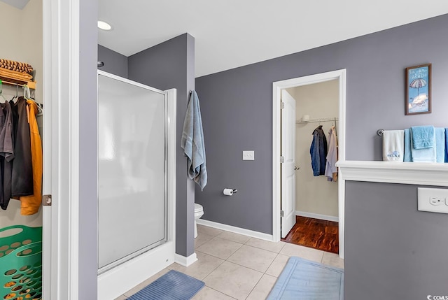 bathroom featuring toilet, tile patterned floors, and a shower with shower door