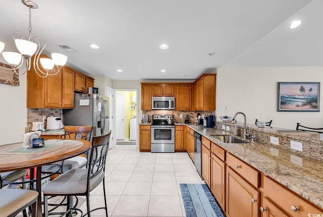 kitchen featuring pendant lighting, sink, light tile patterned floors, stainless steel appliances, and light stone countertops