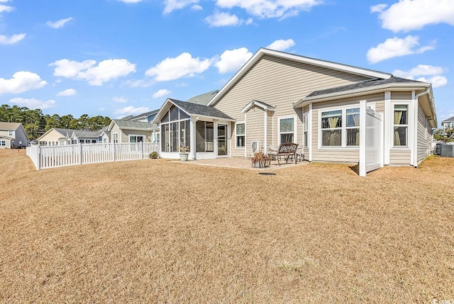 rear view of property featuring a yard, a patio area, and a sunroom