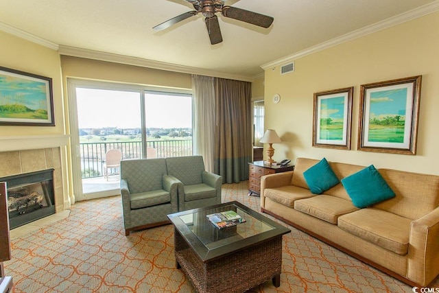 living room with a tile fireplace, crown molding, and ceiling fan