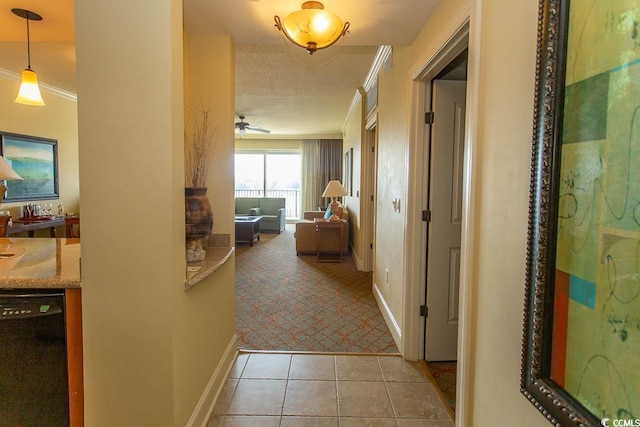 hallway with crown molding, a textured ceiling, and light tile patterned flooring