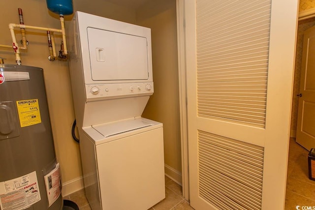 clothes washing area featuring light tile patterned floors, water heater, and stacked washing maching and dryer