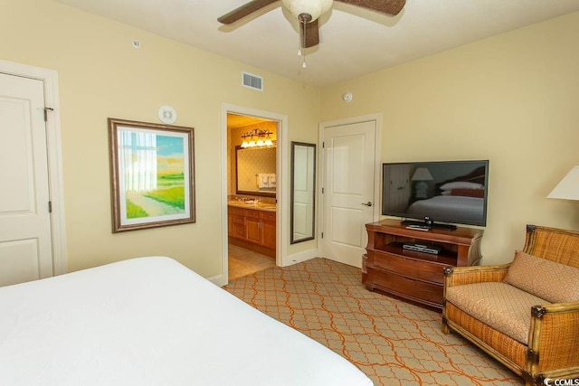 bedroom featuring light colored carpet, ceiling fan, and ensuite bathroom