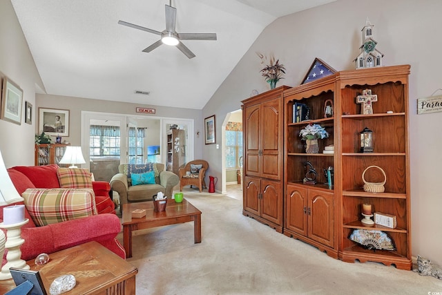 living room with lofted ceiling, visible vents, light carpet, and a ceiling fan