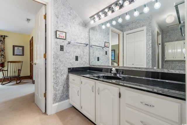 bathroom with vaulted ceiling, vanity, and a textured ceiling