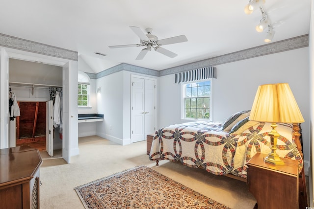 carpeted bedroom with multiple closets, ceiling fan, and rail lighting