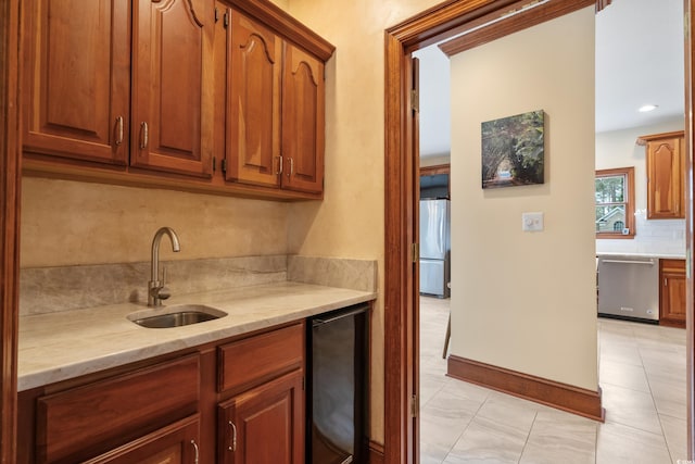 kitchen with appliances with stainless steel finishes, sink, beverage cooler, decorative backsplash, and light stone counters