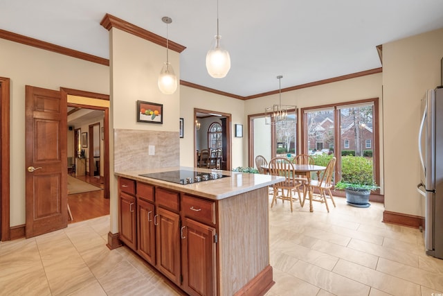 kitchen featuring black electric stovetop, crown molding, stainless steel fridge, and hanging light fixtures