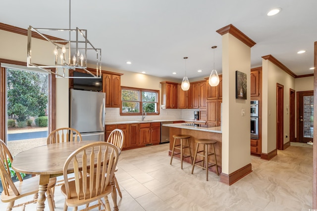 kitchen featuring appliances with stainless steel finishes, sink, backsplash, hanging light fixtures, and ornamental molding