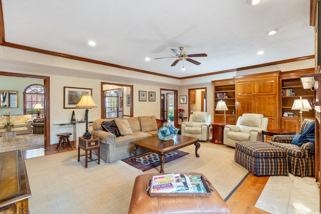 living room with ornamental molding, a textured ceiling, ceiling fan, and light hardwood / wood-style floors