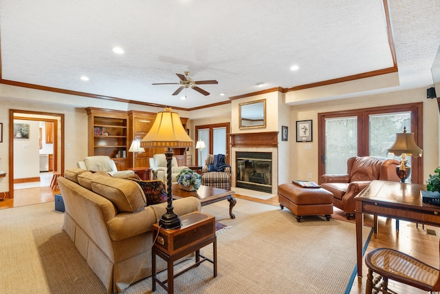 living room with ceiling fan, light hardwood / wood-style flooring, ornamental molding, and a textured ceiling