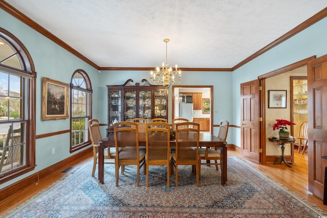 dining space featuring ornamental molding, a chandelier, hardwood / wood-style floors, and a textured ceiling