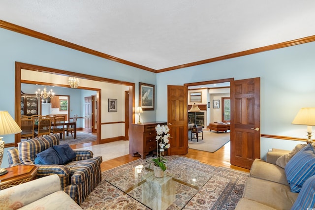 living room with an inviting chandelier, light hardwood / wood-style flooring, ornamental molding, and plenty of natural light