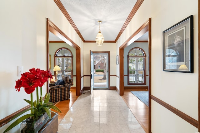 entrance foyer with crown molding, a healthy amount of sunlight, a textured ceiling, and an inviting chandelier