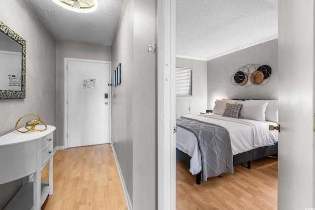 bedroom with crown molding, a textured ceiling, and light wood-type flooring