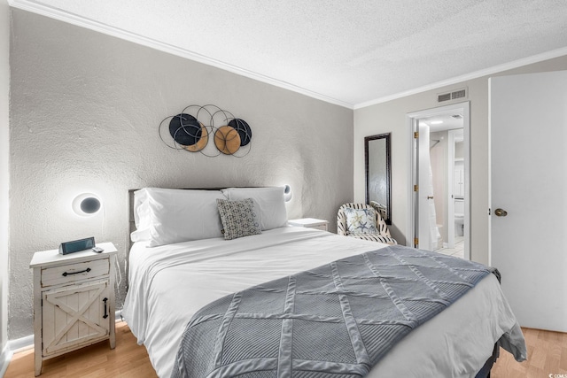 bedroom featuring ensuite bath, ornamental molding, a textured ceiling, and light wood-type flooring