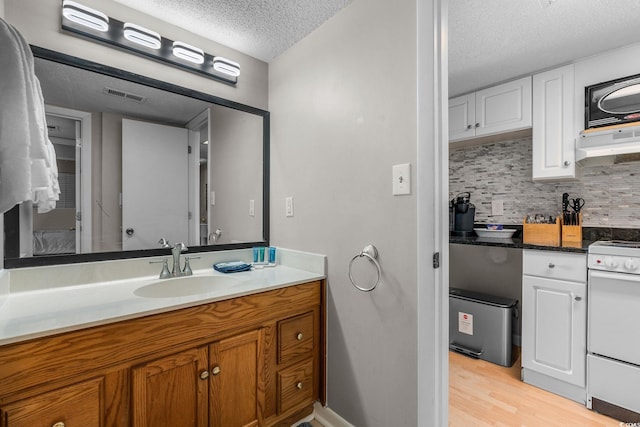 bathroom with hardwood / wood-style flooring, vanity, a textured ceiling, and backsplash