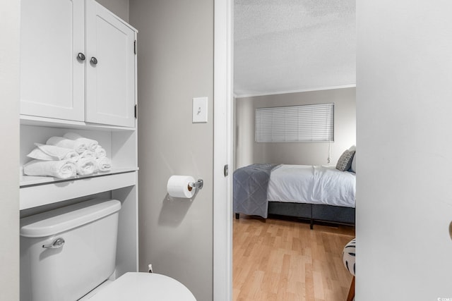 bathroom featuring wood-type flooring, a textured ceiling, and toilet