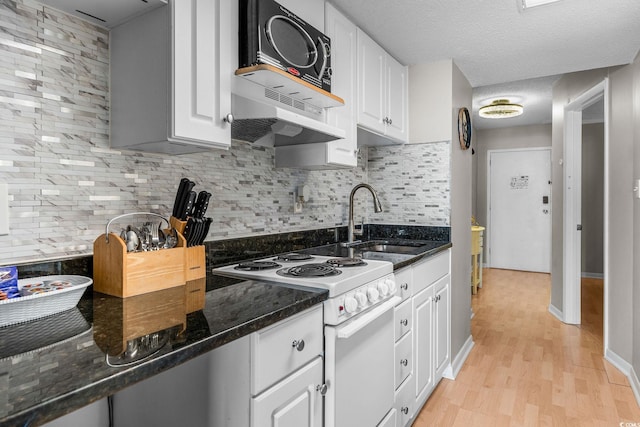 kitchen featuring sink, light hardwood / wood-style floors, white cabinets, white electric stove, and dark stone counters