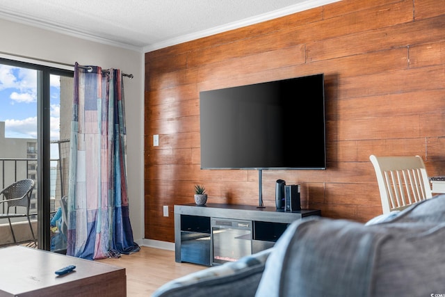 living room featuring crown molding, light wood-type flooring, a textured ceiling, and wooden walls