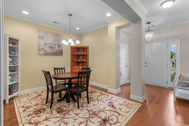 dining space featuring ornamental molding, hardwood / wood-style floors, and a notable chandelier