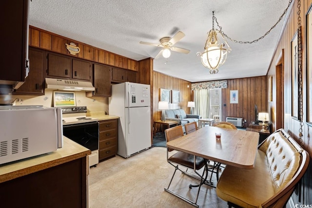 kitchen with wood walls, a textured ceiling, ceiling fan, pendant lighting, and white appliances