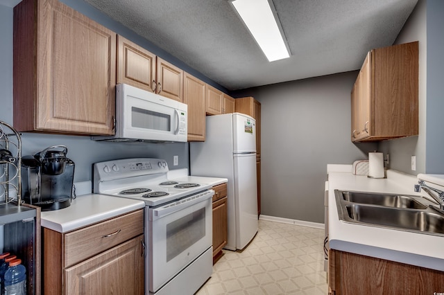 kitchen featuring white appliances, sink, and a textured ceiling