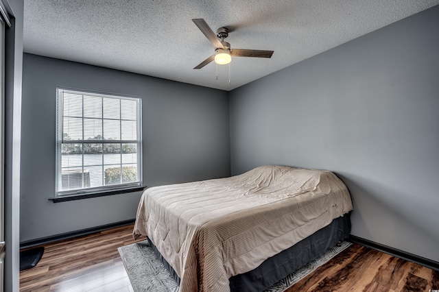 bedroom featuring ceiling fan, wood-type flooring, and a textured ceiling