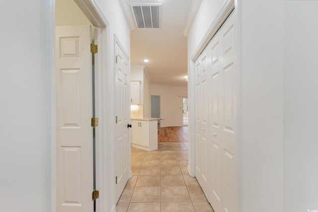 hallway with light tile patterned floors, visible vents, and crown molding