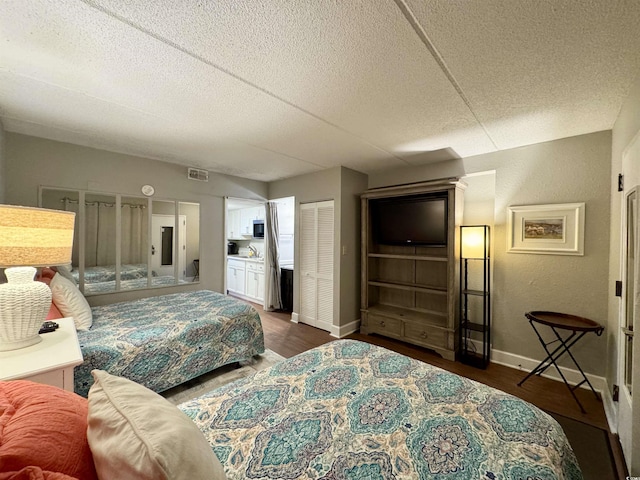 bedroom with ensuite bathroom, dark hardwood / wood-style flooring, and a textured ceiling