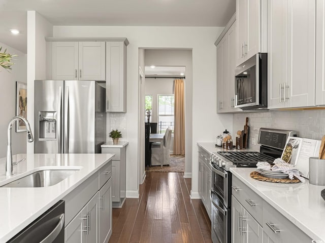 kitchen featuring appliances with stainless steel finishes, dark wood finished floors, light countertops, and a sink