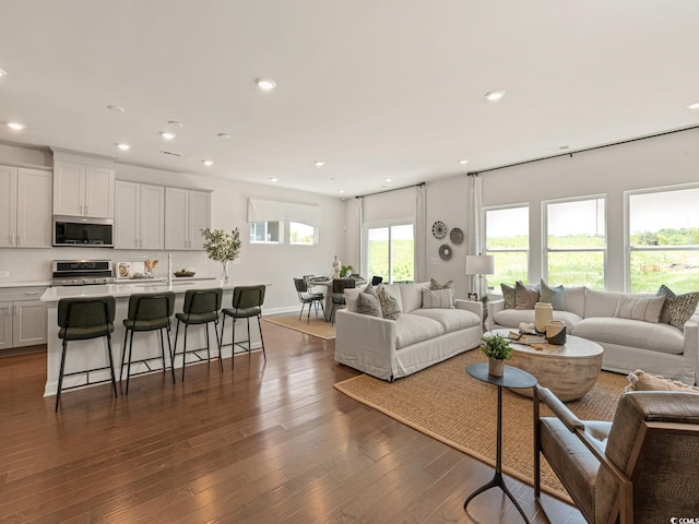 living room with recessed lighting, dark wood-style flooring, and baseboards