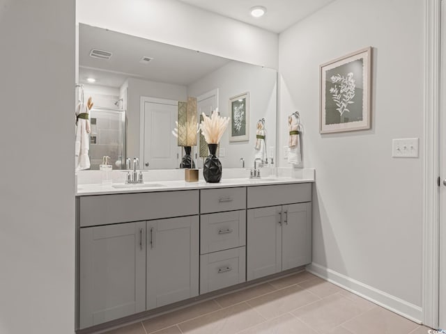 full bath featuring double vanity, a stall shower, baseboards, and a sink