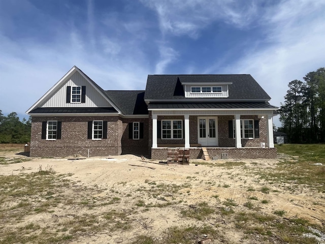 view of front of property with board and batten siding, crawl space, covered porch, french doors, and brick siding