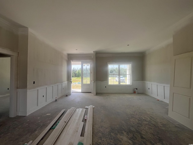 unfurnished room with a decorative wall, crown molding, and wainscoting