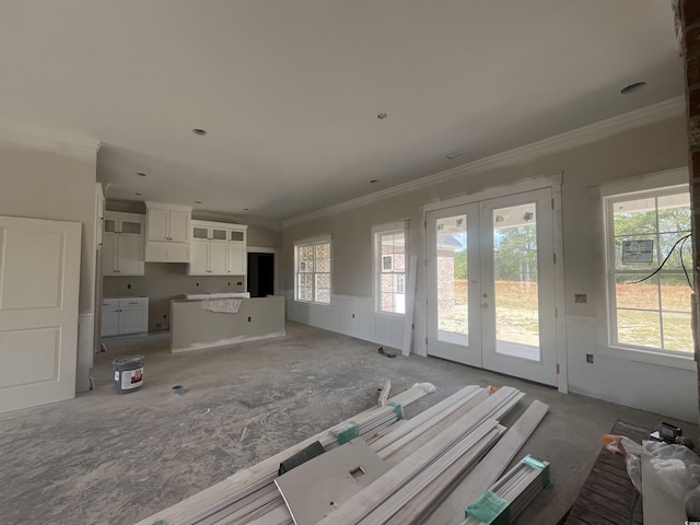 unfurnished living room featuring wainscoting, ornamental molding, and french doors