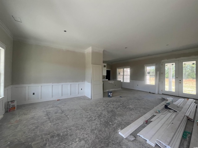 unfurnished living room with wainscoting, a decorative wall, ornamental molding, and french doors