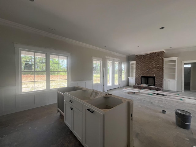 living area with wainscoting, crown molding, and a healthy amount of sunlight