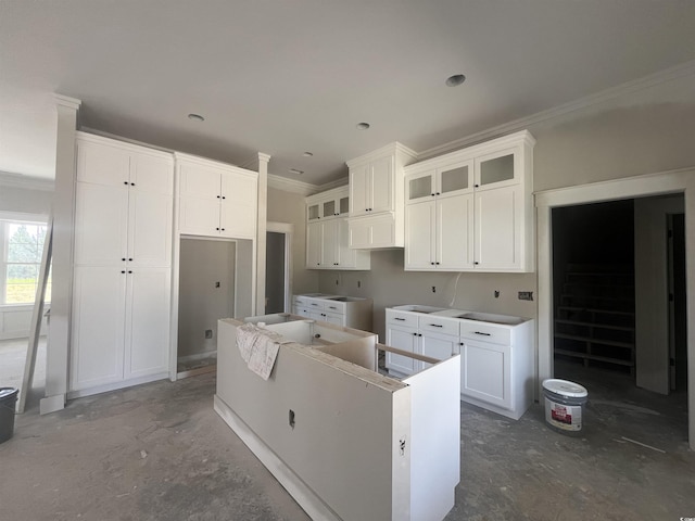 kitchen with glass insert cabinets, a kitchen island, white cabinetry, and ornamental molding