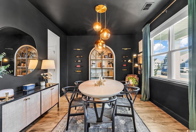 dining area with light wood-style floors, baseboards, and visible vents